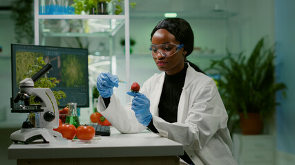 Chemist scientist injecting strawberry with organic liquid examining dna test of fruits for botany experiment. Biochemist working in pharmaceutical laboratory testing health food for medical expertise