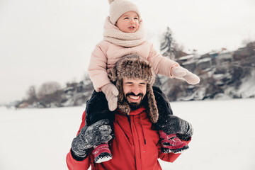 Canvas Print - Happy loving family! Father and his baby are playing and hugging outdoors. Little child and daddy on a snowy winter walk in nature. Concept of the first long-awaited winter snowfall. copy space