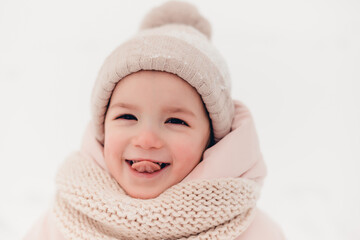 Canvas Print - Happy laughing girl wearing a pink jacket, scarf and hat, playing in a beautiful snowy winter walk. Girl enjoys winter, frosty day. Playing with snow on winter holidays. Winter holidays concept.