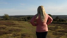 Woman With Blonde Hair Wearing Pink Outdoors Jacket Looking At The Beautiful Landscape In South Of Sweden. Footage Made At Brösarps Backar, Sweden Just Before Sunset.