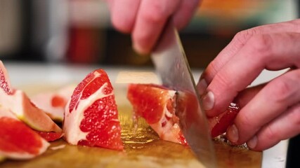 Wall Mural - The male chef cleans and cuts grapefruit on a wooden cutting board in the restaurant's kitchen. Close-up of the hands. Cooking.