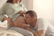 © New Africa - Young pregnant woman with her husband in bedroom, closeup