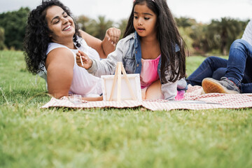 Wall Mural - happy indian family having fun painting with children outdoor at city park - main focus on girl face