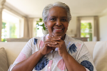 Portrait of senior african american woman sitting on sofa looking at camera and smiling