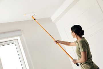 Sticker - Young woman painting ceiling with white dye indoors, space for text