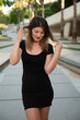 Young attractive shy woman wearing black stylish dress looking down walking in the street