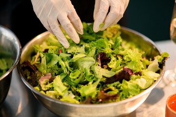 Wall Mural - Salad bowl with arugula and salad leaves and other greens. Chef prepares healthy meal.