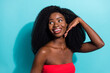 Photo of charming young dark skin woman look empty space hold hand face isolated on teal color background