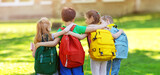 Fototapeta  - Group of children with rucksacks standing in the park near the school
