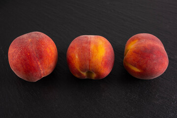 Wall Mural - ripe three peaches lie on a black background