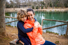 Son Embracing Mom Against Pond In Park