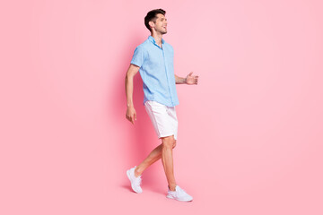 Wall Mural - Profile photo of positive cheerful guy enjoy promenade wear blue shirt shorts sneakers isolated on pink color background