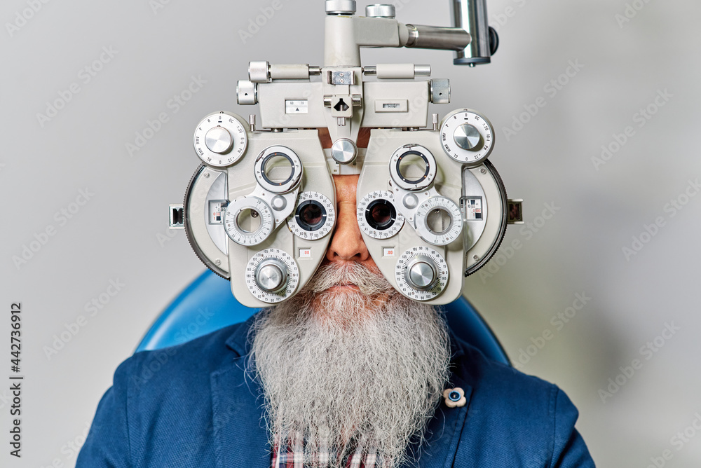 Senior male with phoropter during eye examination