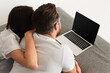 © LIGHTFIELD STUDIOS - Back view of young couple lying near laptop with blank screen on bed