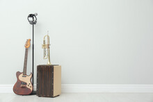 Electric Guitar, Trumpet And Microphone Near White Wall Indoors, Space For Text. Musical Instruments