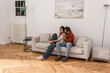 © LIGHTFIELD STUDIOS - Man embracing smiling girlfriend on couch