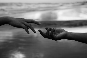 Helping hands abstract art in black and white background. Hands of two people reaching out each other. Hope, kindness and humanity concepts. Partnership and relationship concept.