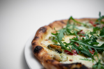 closeup of seafood pizza with shrimp, mussels and arugula on white background