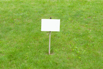 A blank white warning board on the lawn with copy space