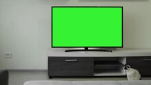 Lcd TV 55 Inches With Green Screen Chromakey Is In Empty Modern Interior Apartment. Domestic Cat Sits Near Furniture In Living Room, Nobody. Streaming Broadcast. Sports Competition. Movie