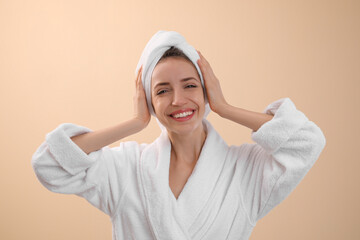 Poster - Beautiful young woman with hair wrapped in towel after washing on beige background