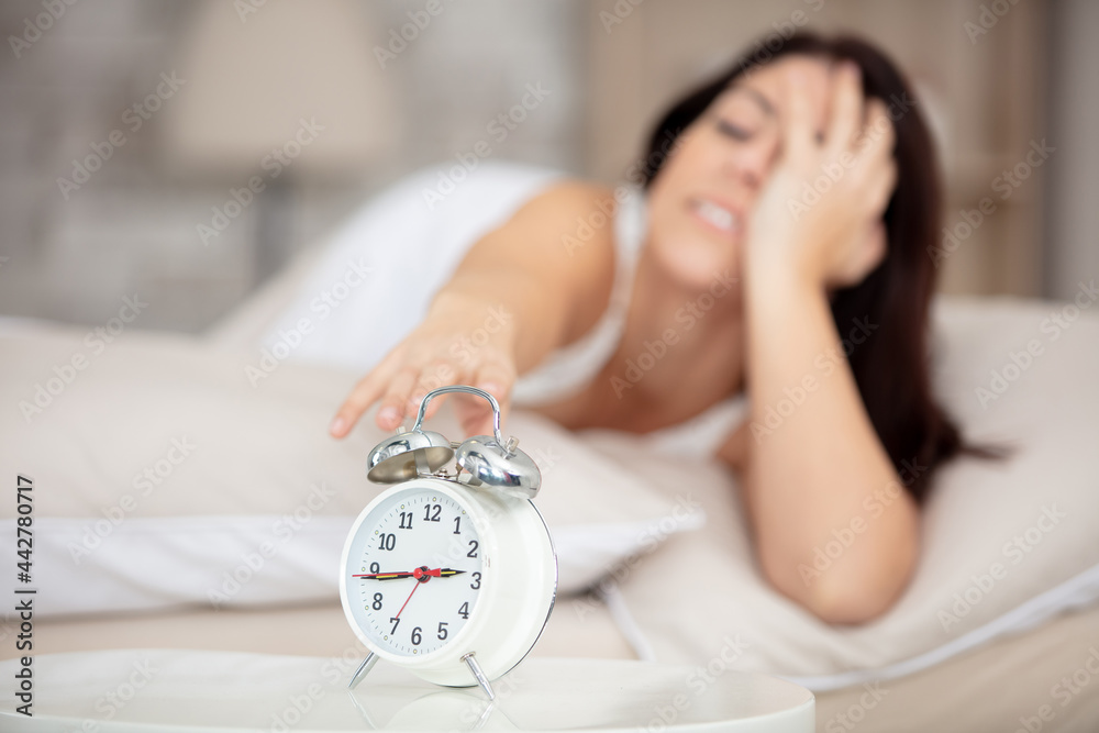 young sleepy woman turning alarm clock off - obrazy, fototapety, plakaty 