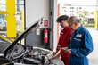 © godji10 - Elderly vehicle mechanic holding tablet maintenance the automotive engine in an auto repair service center. Professional senior car mechanic with automobile team working in the garage workshop