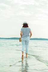 Wall Mural - woman in white clothes walking by sea beach