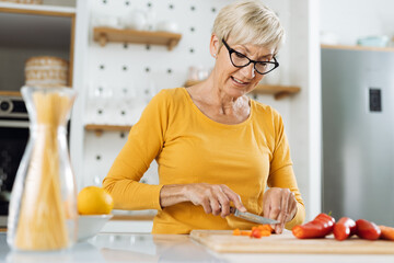 Happy senior woman preparing healthy meal in the kitchen