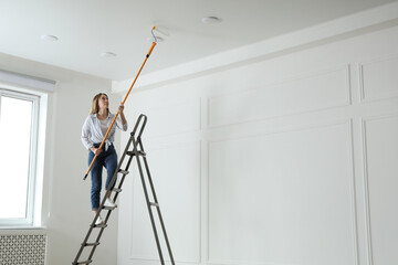 Canvas Print - Young woman painting ceiling with white dye indoors, space for text