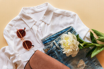 feminine summer fashion flat lay with blouse, handbag, sunglasses and white peony flower on beige ba