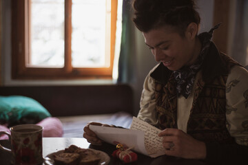 queer asian inside cabin opens presents and reads letter smiling