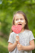 © Анжелла Антоновская - Little girl licking big heart-shaped lollipop