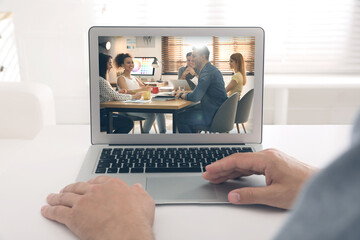 Poster - Man attending online video conference via modern laptop at table, closeup