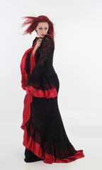 Sticker - full length portrait of red haired woman wearing long black gothic vampire gown. standing pose on white studio background