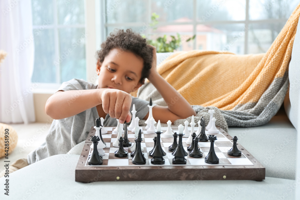 Cute African-American boy playing chess at home