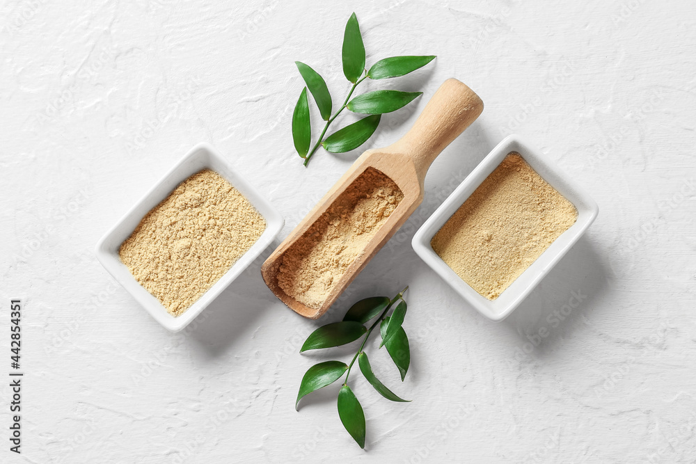 Bowls with ginger powder and scoop on white background
