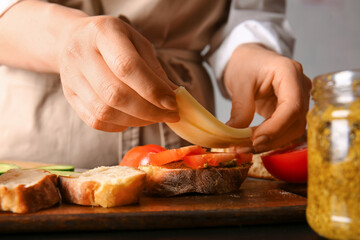 Woman preparing tasty sandwiches on table, closeup