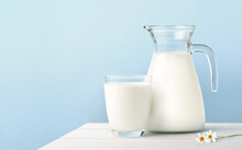 Glass And Jug Of Fresh Milk On White Wooden Table.
