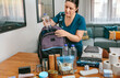 © David Pereiras - Woman putting a water bottle to prepare emergency backpack in living room