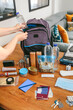© David Pereiras - Unrecognizable woman putting a water bottle to prepare emergency backpack in living room