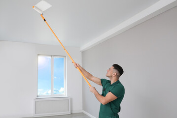 Canvas Print - Man painting ceiling with roller in room