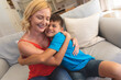 © WavebreakMediaMicro - Caucasian mother and son sitting on couch embracing and smiling at home