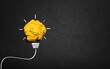 © chathuporn - creative Idea, yellow crumpled paper ball shaped like an electric bulb on black paper or blackboard
