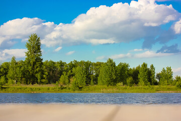 Green tree tops in a forest park zone of a coastal strip. Water bodies, lakes, rivers, ponds. National reserve. Amazing natural landscape at sunny summer day. Beautiful blue cloudy sky above trees.