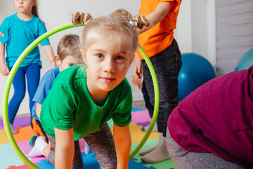 Wall Mural - Curly girl crawling on colorful floor through hula hoops