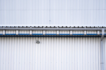 Wall Mural - White corrugated iron sheet used as a facade of a warehouse or factory. Texture of a seamless corrugated zinc sheet metal aluminum facade. Architecture. Metal texture.