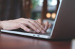© tippapatt - Woman hands typing on laptop computer on wooden table at home or coffee shop, searching information on web, browsing the internet, work from anywhere