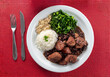 Traditional Brazilian feijoada food from above on a red table