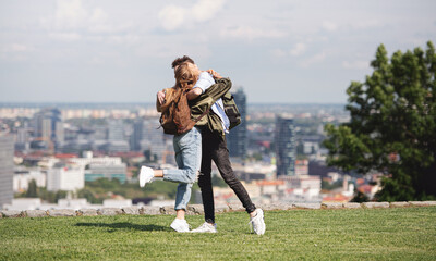 Wall Mural - Young couple travelers in city on holiday, hugging. Cityscape in the background.